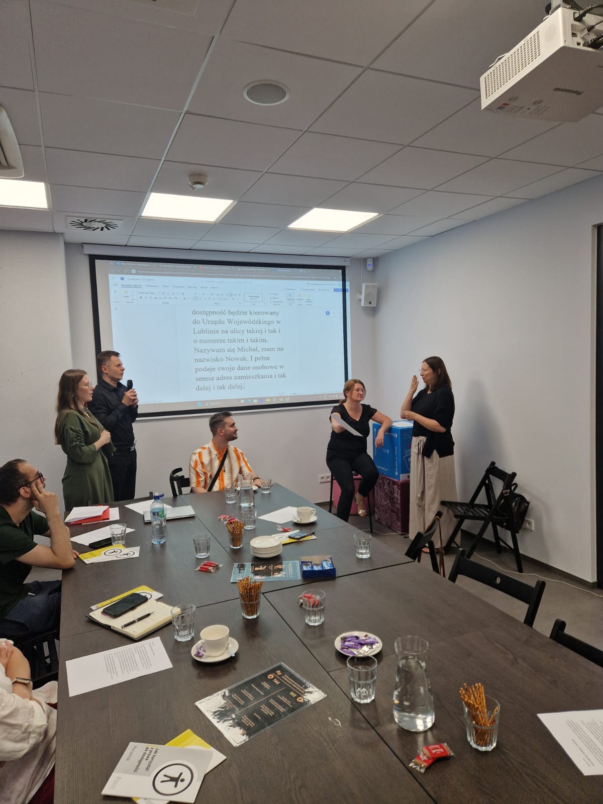 Grupa osób uczestniczy w warsztacie. Toczy się dyskusja.