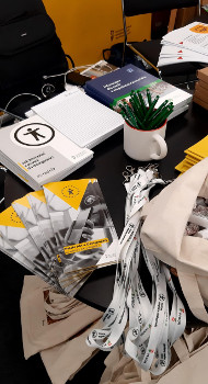 materiały PFRON na stoliku: ulotki, torby, smycze, długopisy