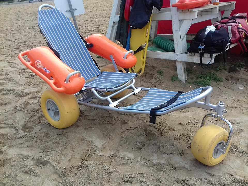 Na piasku stoi wózek do poruszania się po plaży dla osób z niepełnosprawnościami